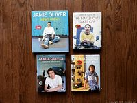 Four hardcover Jamie Oliver cookbooks titled Jamie's Kitchen, The Naked Chef Takes Off, Jamie's Dinners, and The Naked Chef on a wooden surface.