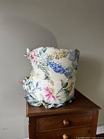 Side view of the rolled floral duvet showing colorful flower patterns and ruffled edges, placed on a wooden chest.