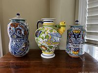 Photo of three large hand painted Italian ceramic containers with lids displayed on a wooden surface.