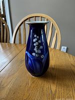 Blue porcelain vase with white floral design and gold accents on wooden table