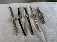 Five watches side by side on fabric surface