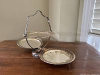 Three-tier metal high tea stand unfolded showing three circular plates with ornate rims and handle