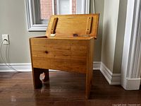 Chest angled open showing hinged lid with wooden support braces, pine wood grain visible.