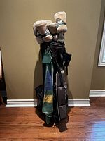 Black golf stand bag with attached clubs, towel and umbrella