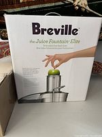 Photo of Breville Juice Fountain Elite box with branding and image of juicer showing whole fruit feed chute