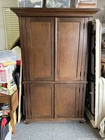 Front view of the Pottery Barn Sonoma Armoire in wooden finish, showing the four-panel wrap-around doors and crown molding detail.