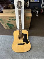 Full front view of the Sawtooth acoustic dreadnought guitar showing natural wood finish, black pickguard, and bear claw inlays on fretboard.