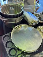 Overview of some of the pans stacked together, showing standard and mini Bundt pans, pie weights in a plastic container, and a round tart pan.