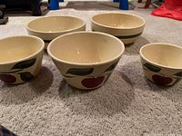 Five cream-colored bowls with cherry and leaf design, arranged in a group.