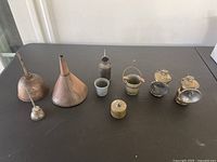 Full lot overview showing all antique metal items arranged in a row on a black table.