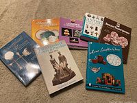 Photo showing seven different books on ceramic arts, porcelain, pottery, flatware, and transferware. Books are stacked and spread out on carpeted floor.