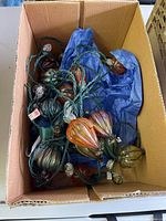 Overhead view of string lights with green and amber decorative bulbs inside a cardboard box lined with blue tissue paper