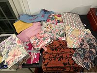 Lot overview showing multiple fabric pieces in various colors and patterns along with a floral storage box.