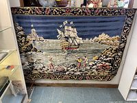 Front view of large hanging fabric pirate ship scene tapestry showing detailed coastal pirate ship and figures