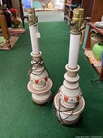 Full view of both ceramic country style table lamps side by side showing their general shape and design.