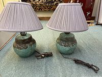Pair of Gonder ceramic base lamps with large gray pleated shades on carpeted surface.