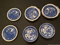 Six blue and white dessert bowls and saucer plates with different scenic patterns and floral borders