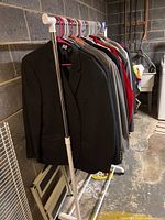 Side view of black and gray men's suit jackets hanging on garment rack