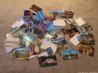 Top-down photo of a spread of assorted vintage travel postcards on carpet, including some with writing and stamps, some blank