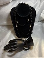 Necklace and bracelet displayed on a black mannequin bust and hand showing the full set with beads and pearls.