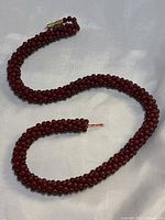 Photo showing broken garnet beaded necklace with visible break in string and gold-tone barrel clasp.