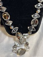 Close-up of clear cut crystal beads showing faceted oval and geometric shapes against a black velvet display.