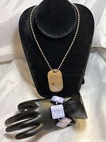 Necklace with metal pendant displayed on black velvet bust, abalone bracelet on black hand display.