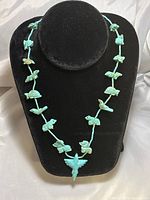 Full view of the necklace displayed on a black velvet bust showing turquoise animal fetishes and beads.