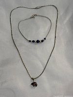 Photo of the sterling silver necklace with a bear pendant alongside the lapis lazuli and silver beaded bracelet on a light fabric background.