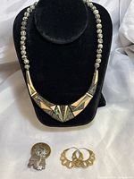 Full view of necklace, brooch pin, and hoop earrings on display against black velvet background