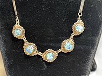 Close-up of necklace front showing five oval opal stones set in ornamental bezels connected by chain links.