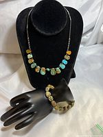 Full view of turquoise necklace on black bust and agate bracelet on black hand display, showing overall set