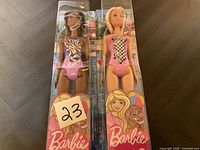 Two new Barbie dolls in original packaging, front view showing swimsuits and box designs.
