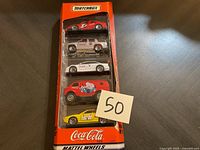 Front angle view of Coca-Cola Matchbox cars set in original packaging showing all five cars vertically aligned.
