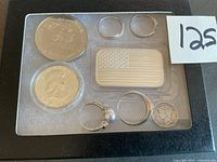 Top view of display box showing rings, coins, and silver flag bar.