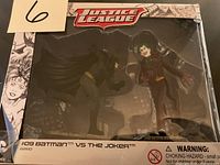 Photo showing boxed Justice League Batman vs The Joker figurines with torn box corner.