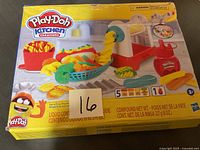 Photo of the Play-Doh Kitchen Creations box front showing images of Play-Doh pasta and fries, with some box damage visible