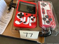 Red handheld game system and matching wired controller in clear plastic packaging