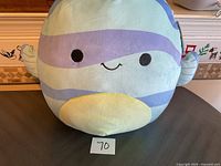 Front view of the Squishmallows LeLand plush toy sitting upright on a flat surface, showing the smiling face and pastel color design.
