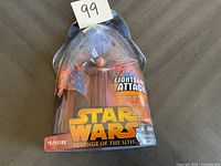 Palpatine figurine in original packaging with Star Wars Revenge of the Sith and Lightsaber Attack graphics, packaging slightly damaged at top.