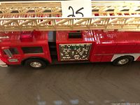 Side view of the vintage red Hess fire truck toy with detailed control panel and beige extendable ladder on top.