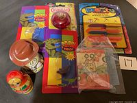 Photo displaying a collection of vintage toys including packaged Grow Dinos, Duncan yo-yo, Party plastic knives, Russian nesting doll, tin toy man with hat, and a small wooden animal toy.