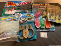 Photo showing the full lot of vintage toys including the helicopter, handcuff keychain, floating boats, and monkey figures.