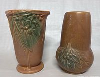 Front view of two McCoy's art pottery vases showing their shape and botanical relief designs.