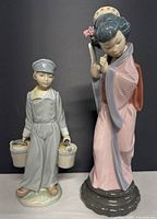 Both figurines side by side on a black background showing overall appearance and height.