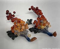 Photo showing pair of vintage agate stone grape clusters, showcasing the polished stones and metal leaves from a side angle.