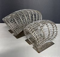 Photo showing two different sized stainless steel floral bouquet arranger stands with curved wire construction on flat bases.