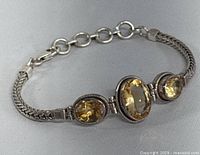 Front view of sterling silver chain bracelet with three yellow citrine stones.