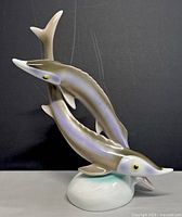 Side angle view of porcelain fish figurine showing intertwined fish and detailed fins.