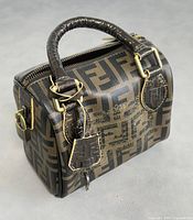 Front angled view showing all-over Zucca print canvas, embossed leather handles, gold-tone hardware and attached padlock with key.